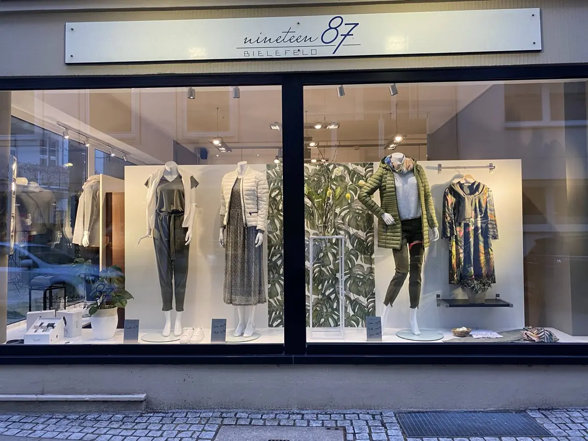 Das beleuchtete Schaufenster von Nineteen87 in der Steinstraße mit Schild über dem Fenster