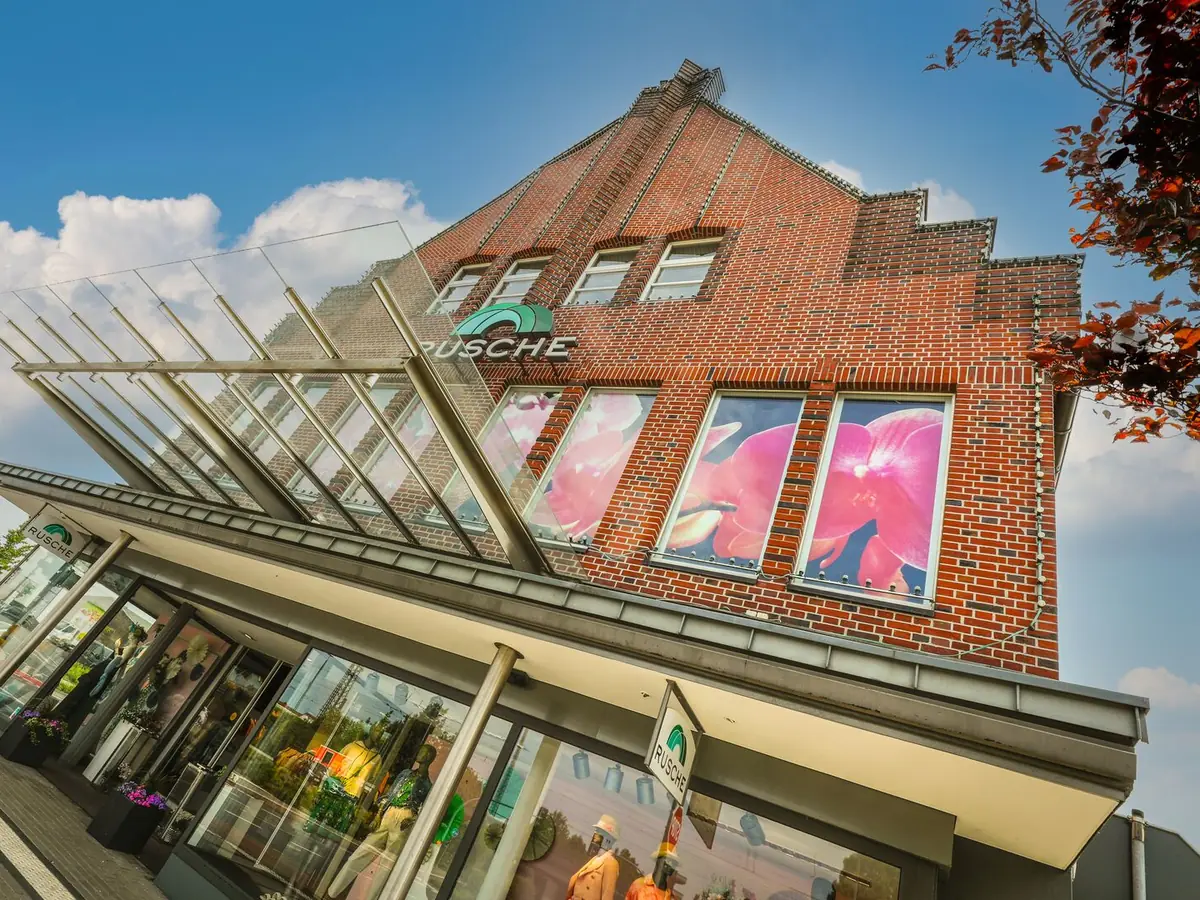 Die Backsteinfassade von Modehaus Rusche in Oelde mit Glasvordach und Schaufenstern