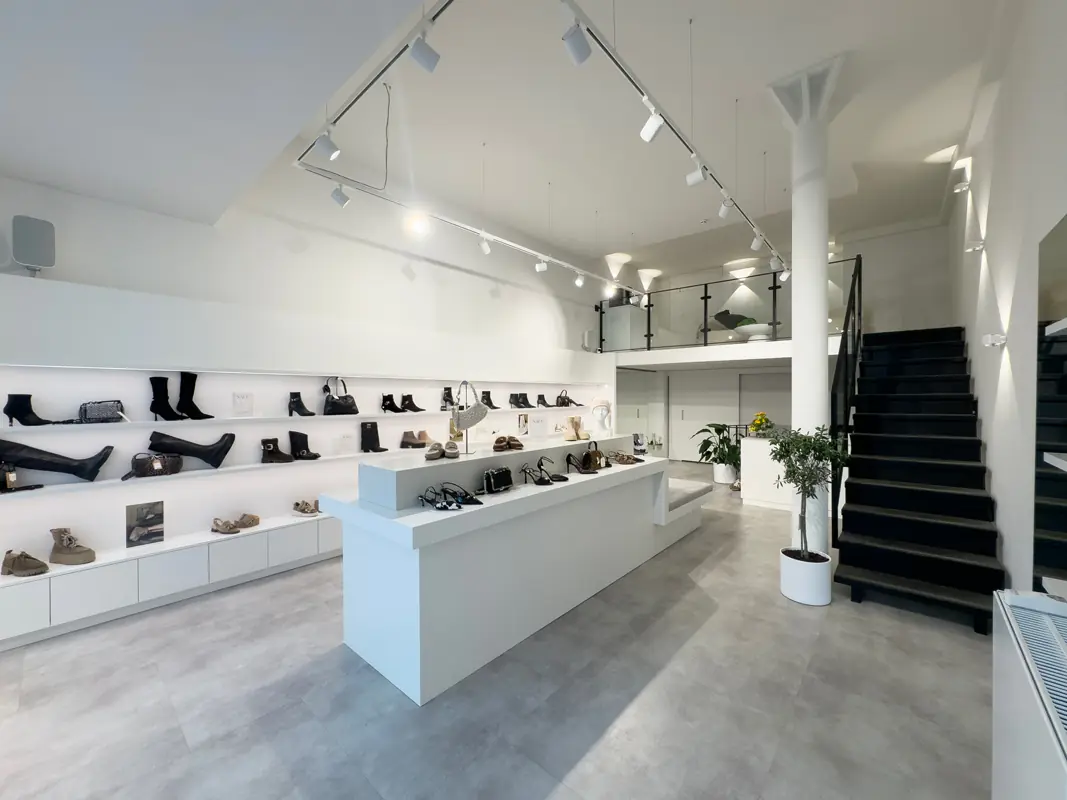 Verkaufsraum von the ordinary in der Rathausstraße mit weißen Regalen, Schuhen und Treppe zur Galerie
